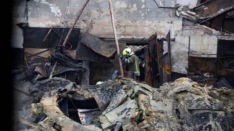 Ein Gebäude liegt nach einem Raketenangriff in Trümmern. In den Trümmern steht ein Feuerwehrmann,