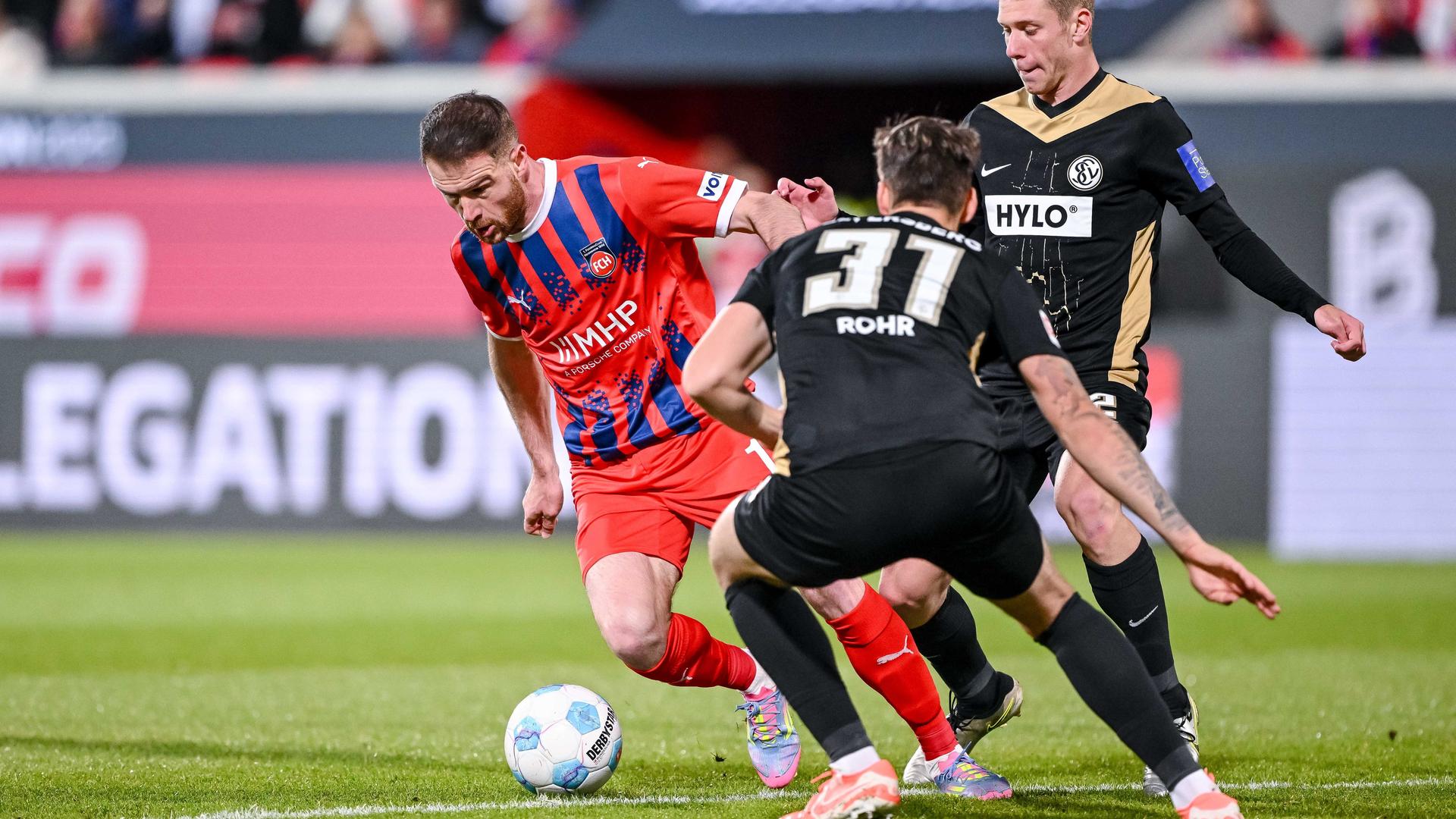 Drei Fußballspieler kämpfen um den Ball.
