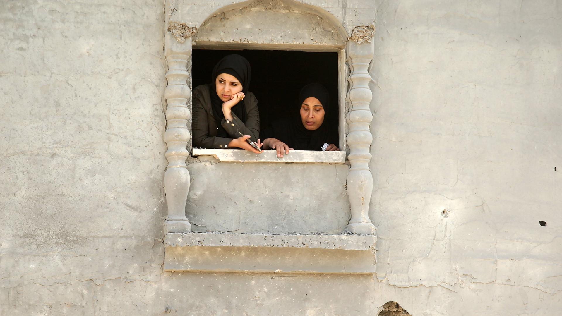 Zwei Frauen schauen aus dem Fenster eines Hauses im Gazastreifen.