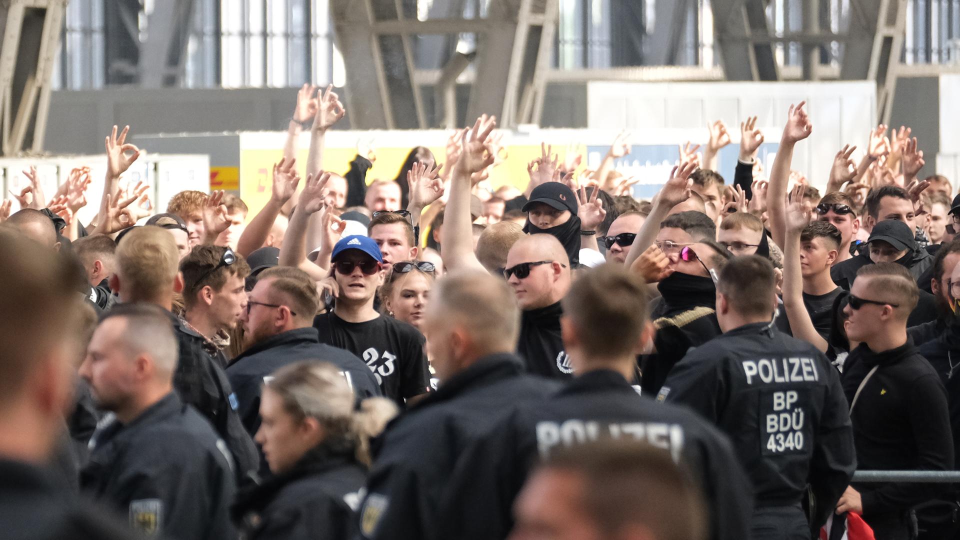 Rechtsextremen versammeln sich im Leipziger Hauptbahnhof, umringt von Polizisten.