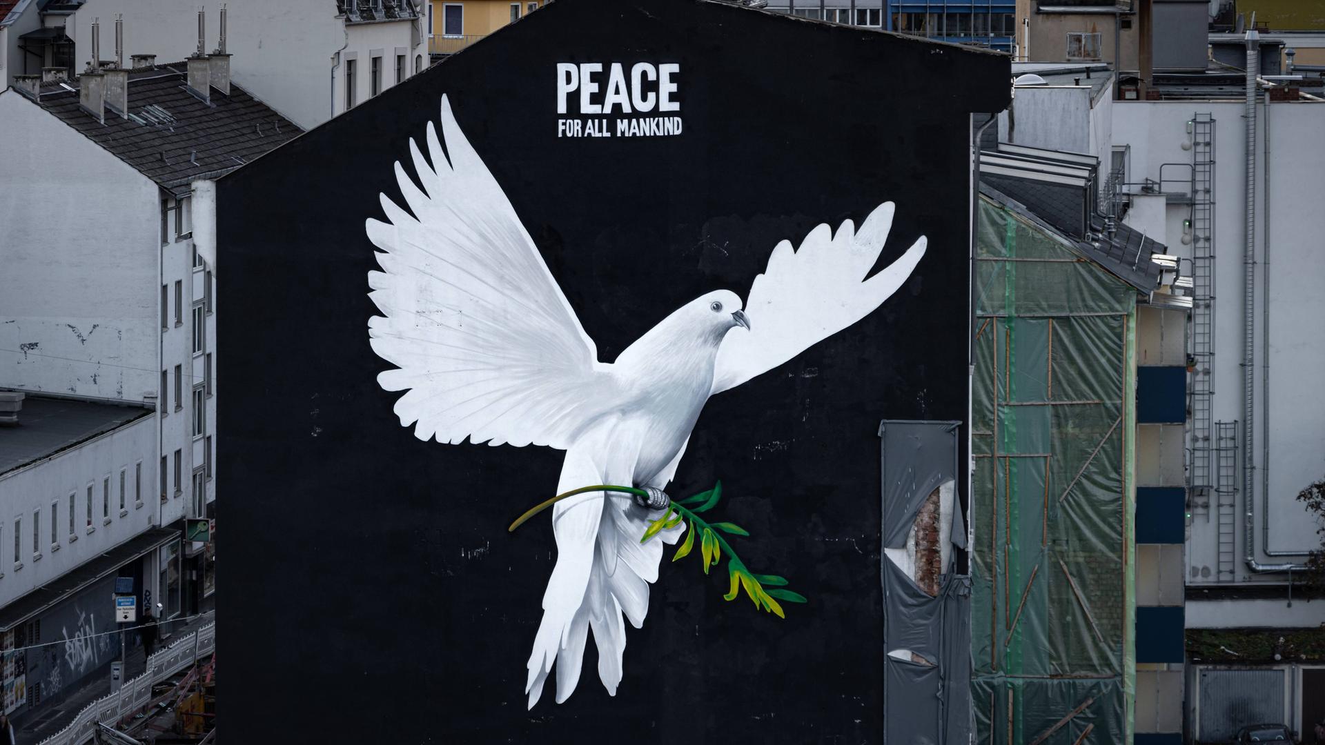 Eine Friedenstaube auf einer Häuserfassade mit der Überschrift "Peace for all mankind"