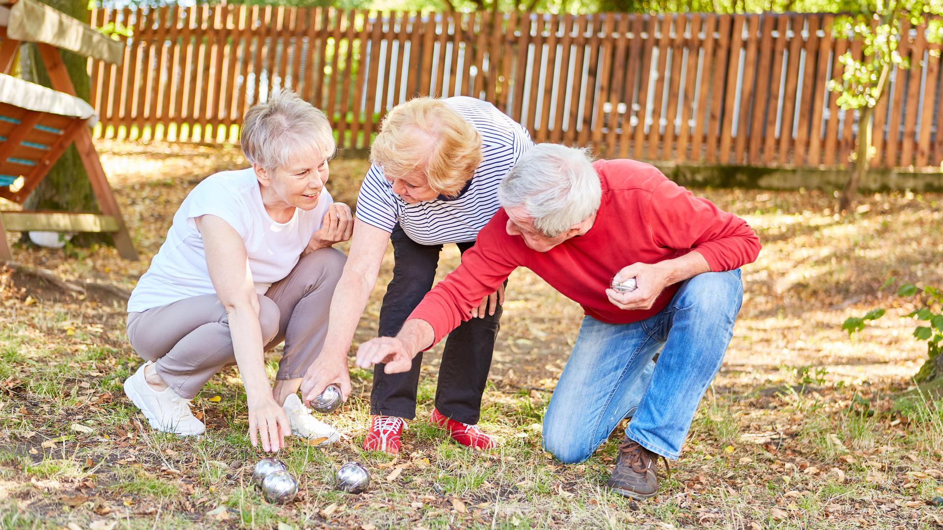 Aktive Seniorinnen und Senioren freuen sich am Boulespiel in einem Garten