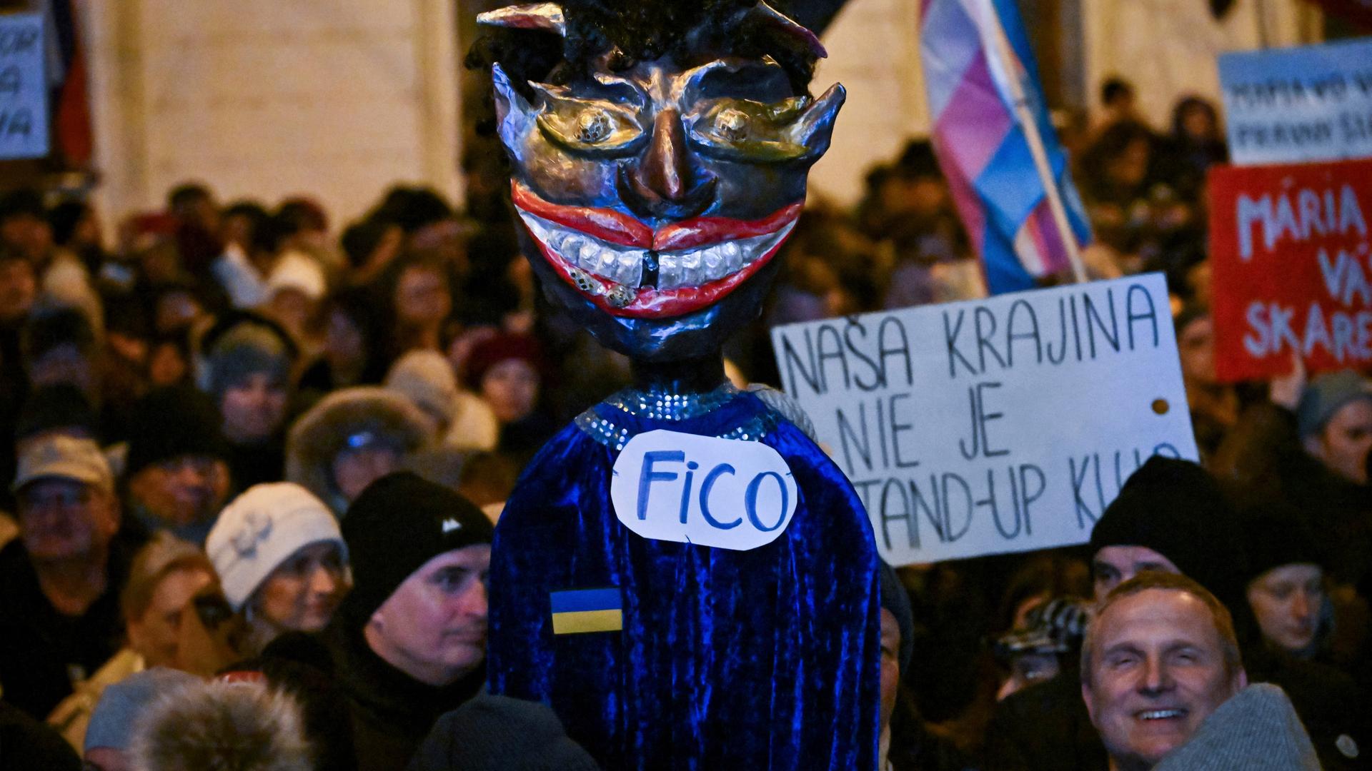 In der slowakischen Hauptstadt Bratislava haben sich Menschen zu einer Demonstration gegen die Regierung versammelt. Sie tragen eine Puppe, die Ministerpräsident Fico als Teufel darstellt und Plakate.