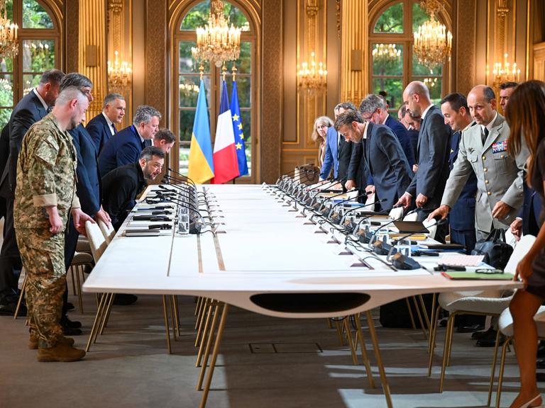 Der französische Präsident Macron und andere Politiker und Militärs begrüßen Wolodymyr Selenskyj im Elysee-Palast am 3. September 2025 an einem großen Tisch mit vielen Mikrofonen