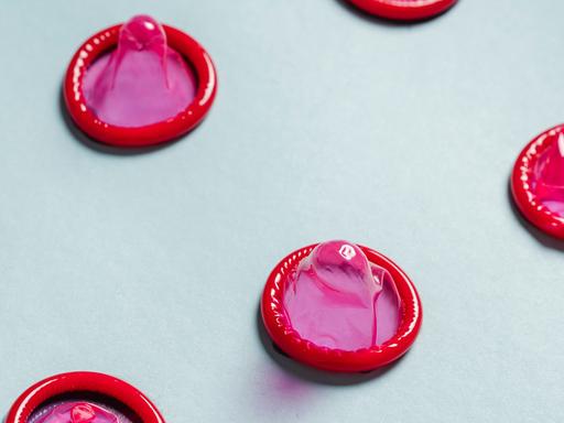 Pinkfarbene Kondome in regelmäßigen Abständen aufgereiht. Pinkfarbene Kondome in regelmäßigen Abständen aufgereiht.