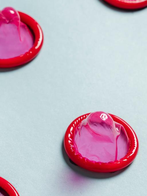 Pinkfarbene Kondome in regelmäßigen Abständen aufgereiht. Pinkfarbene Kondome in regelmäßigen Abständen aufgereiht.