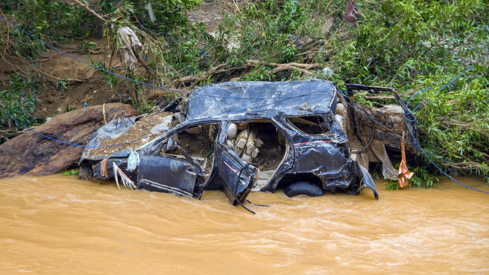 Ein Autowrack liegt an einem Flussufer. Ein Autowrack liegt an einem Flussufer.