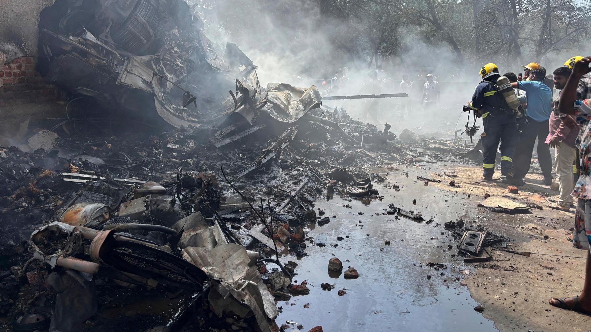 Feuerwehrleute arbeiten an der Absturz-Stelle des Flugzeugs. Trümmer-Teile und Rauch sind zu sehen. Feuerwehrleute arbeiten an der Absturz-Stelle des Flugzeugs. Trümmer-Teile und Rauch sind zu sehen.