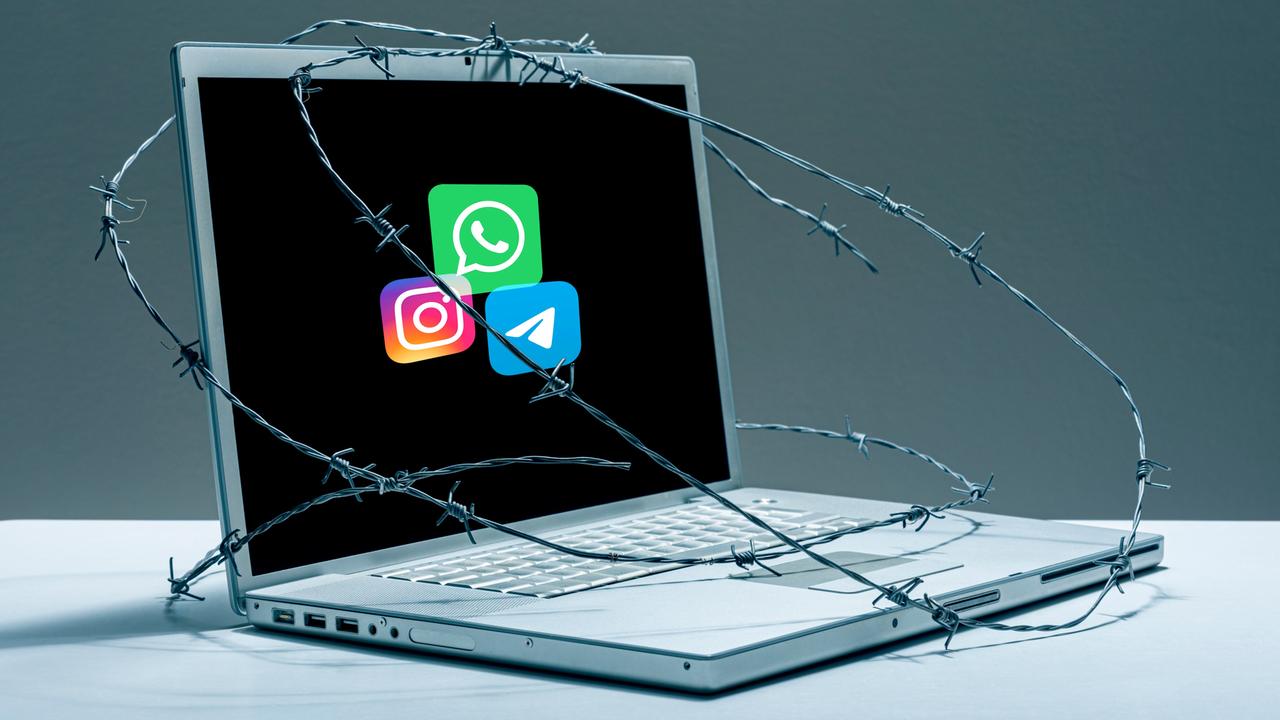 Auf einem mit Stacheldraht umwickelten Laptop sieht man die Logos von Telegram, Instagram und Whatsapp. 