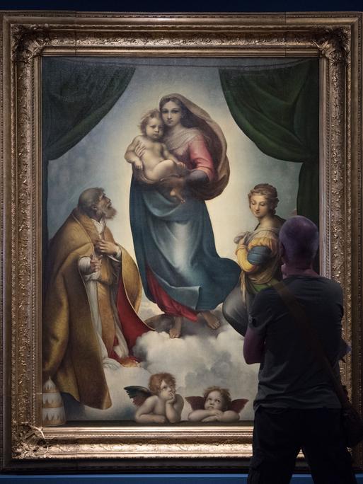 Ein Museumsbesucher betrachtet das Gemälde "Sixtinische Madonna" von Raffael in Dresden.