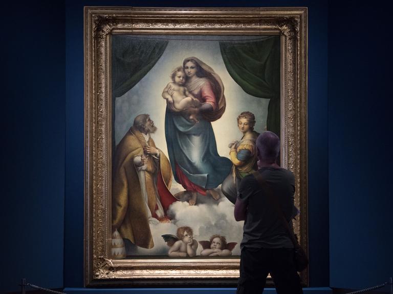 Ein Museumsbesucher betrachtet das Gemälde "Sixtinische Madonna" von Raffael in Dresden.