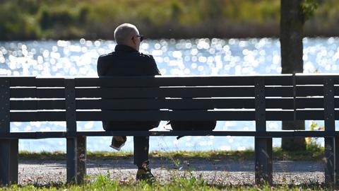 Mann sitzt auf einer Bank im Freien