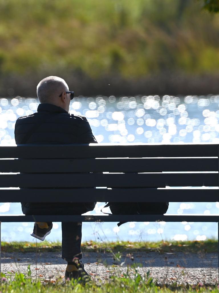Mann sitzt auf einer Bank im Freien