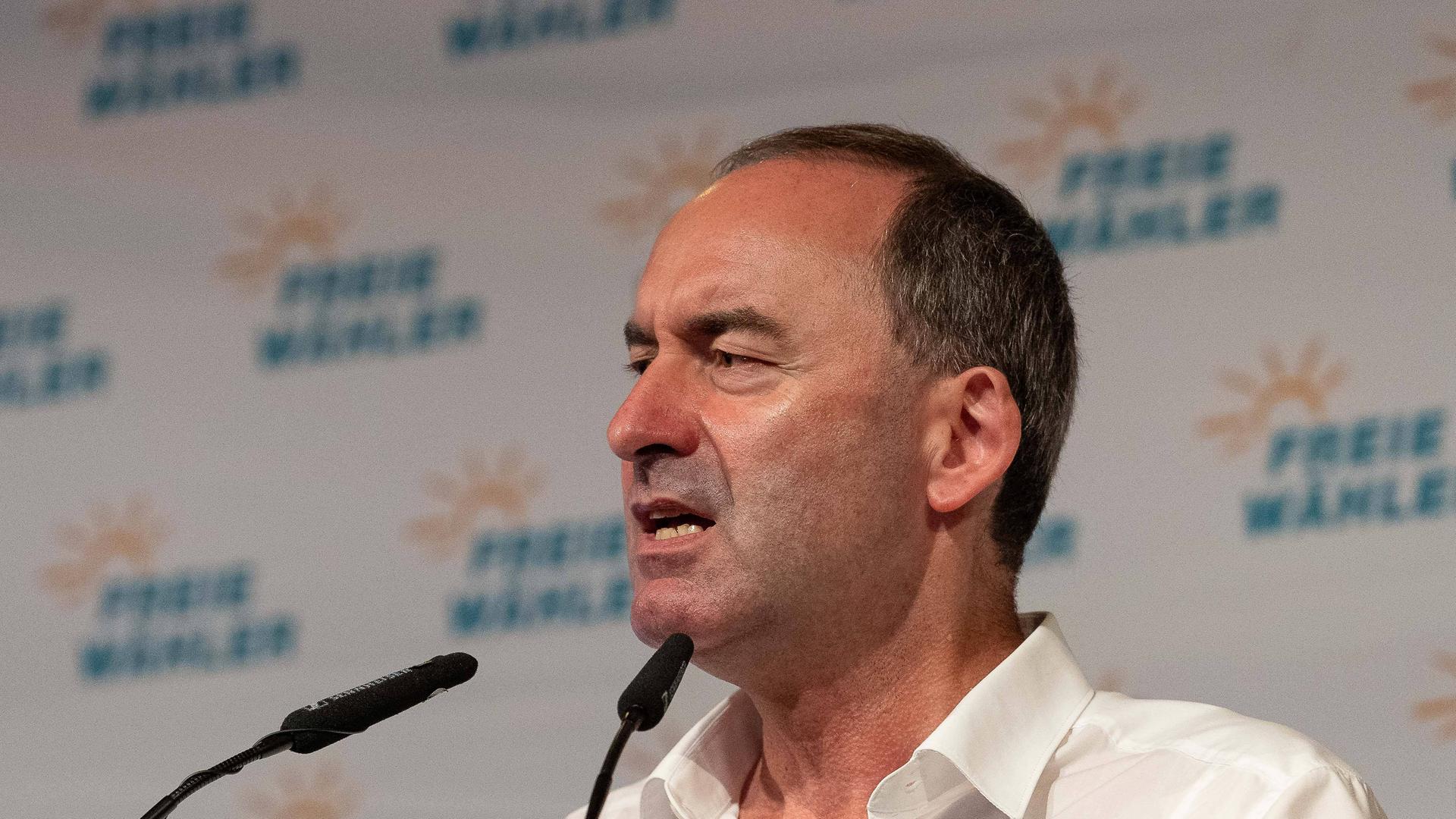 Hubert Aiwanger steht an einem Mikrofon und hält eine Rede, im Hintergrund ist eine Stellwand mit Logos seiner Partei "Freie Wähler" zu sehen.
