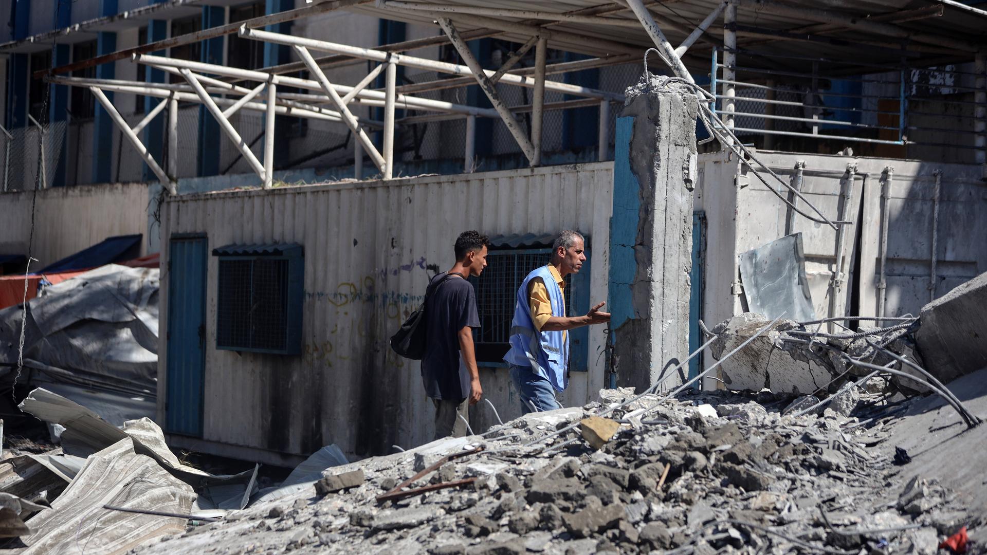 Eine ehemalige Schule im Flüchtlingslager Nuseirat wurde durch israelische Angriffe zerstört. Zwei Personen gehen durch Schutt. 