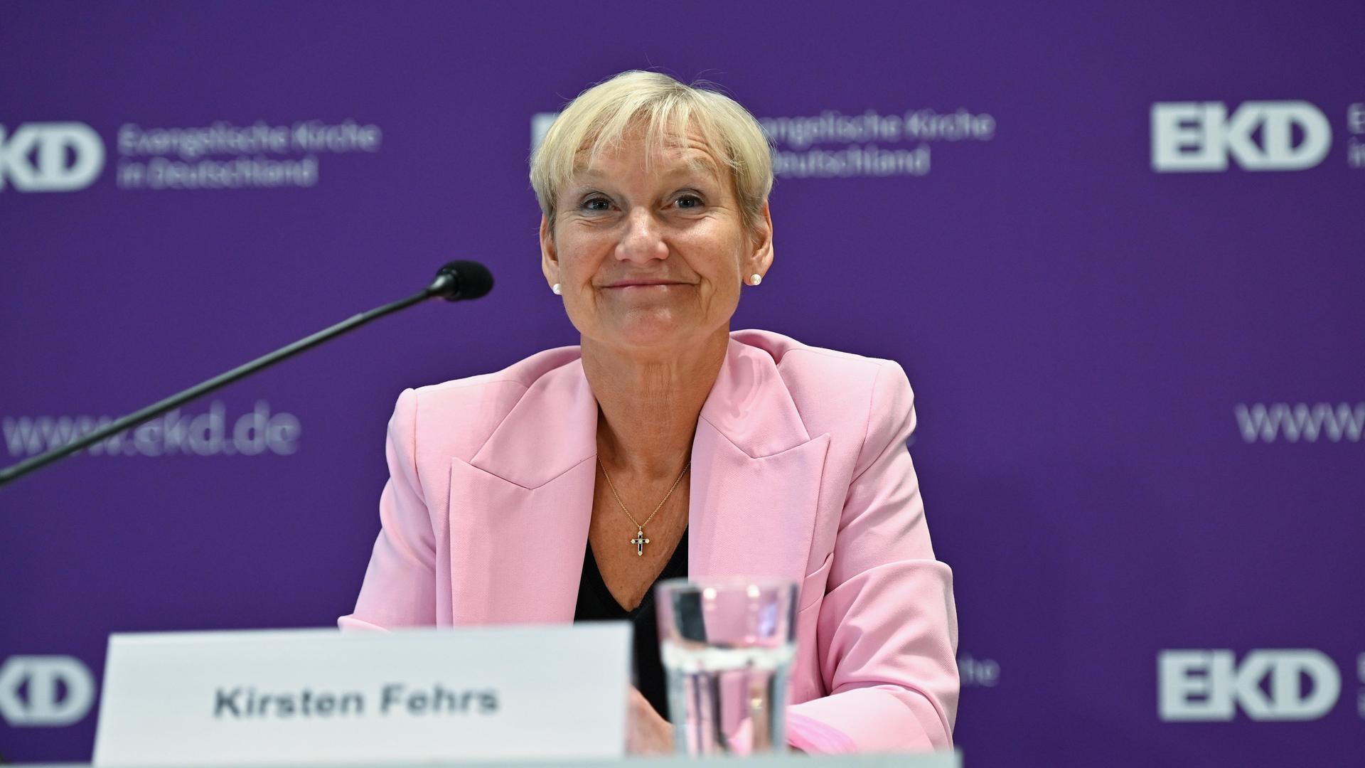 Kirsten Fehrs auf einem Podium. Sie trägt kurzes blondes Haar und lächelt. 