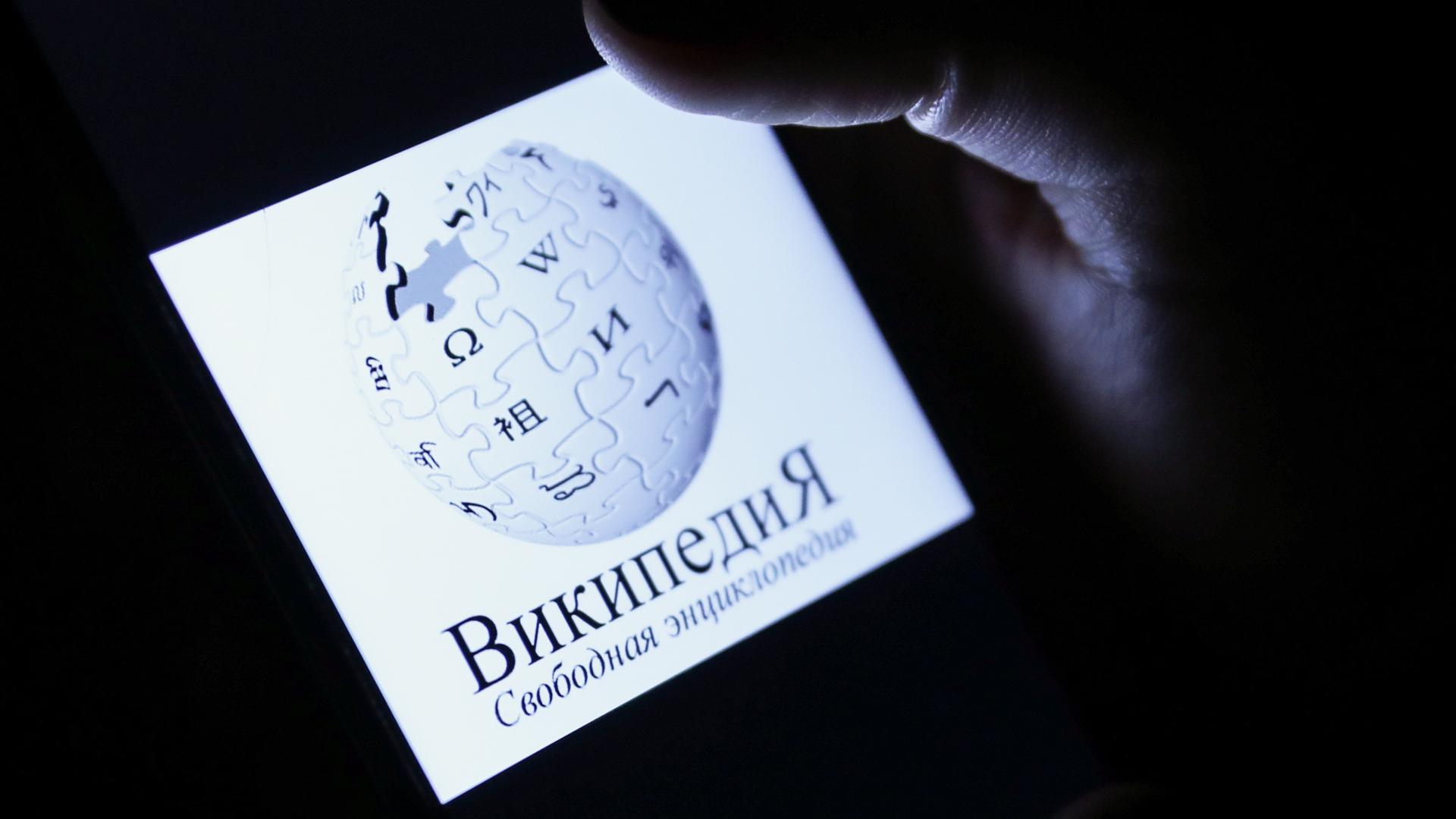 Das Logo von Wikipedia mit russischer Schrift auf eine, Handydisplay.