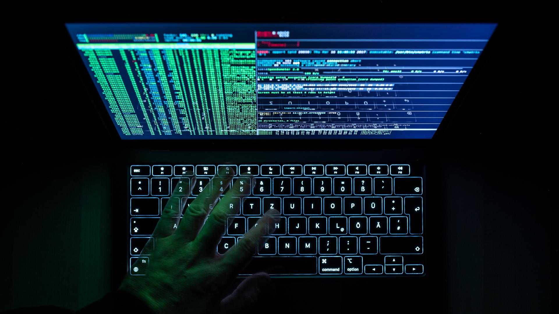 Eine Hackersoftware ist auf einem Laptop geöffnet. Eine Hand liegt auf der Tastatur. 
