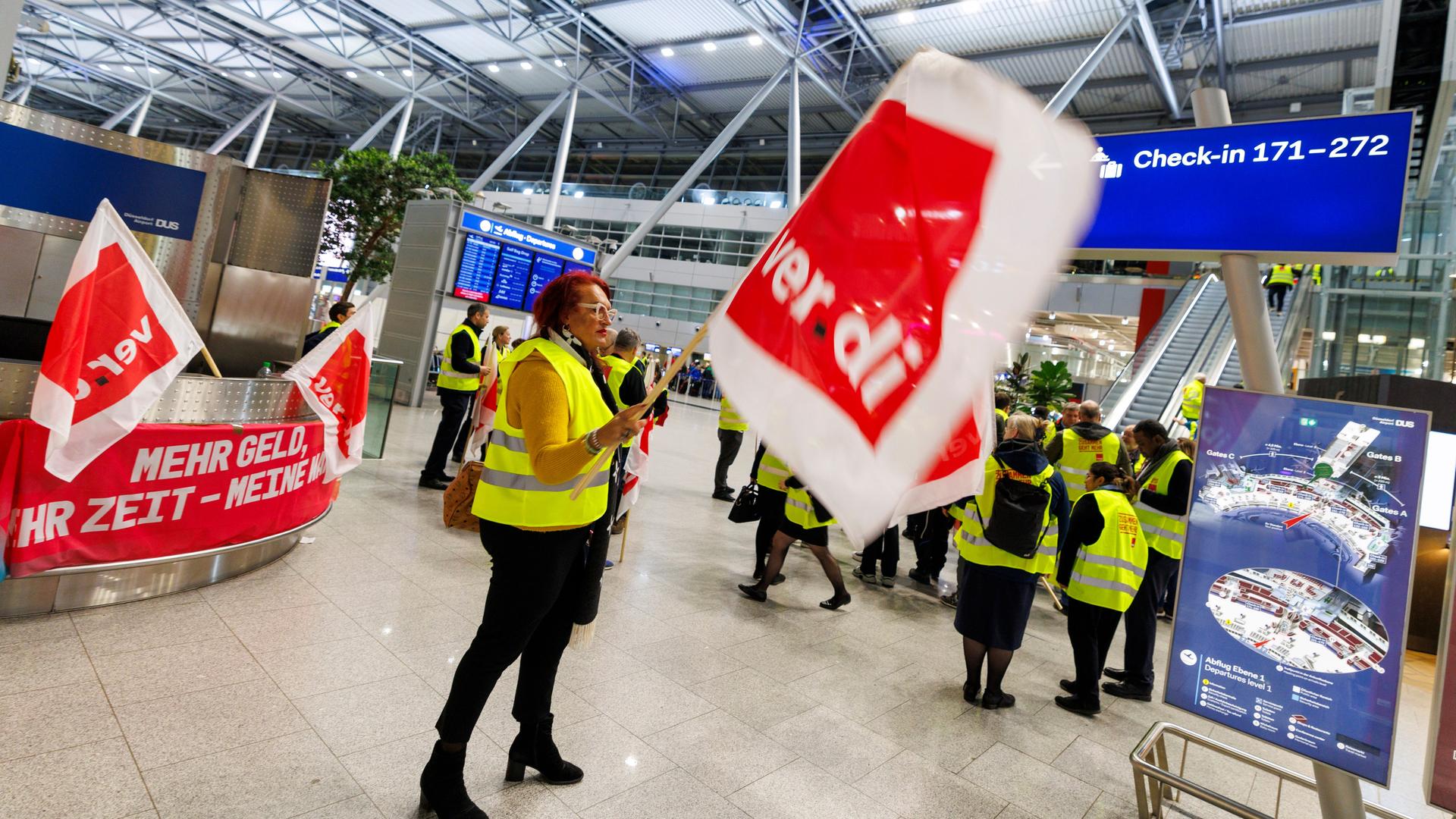 Mitarbeiter des Bodenpersonals stehen mit Fahnen der Gewerkschaft Verdi im Abflugterminal am Flughafen Düsseldorf und streiken. 