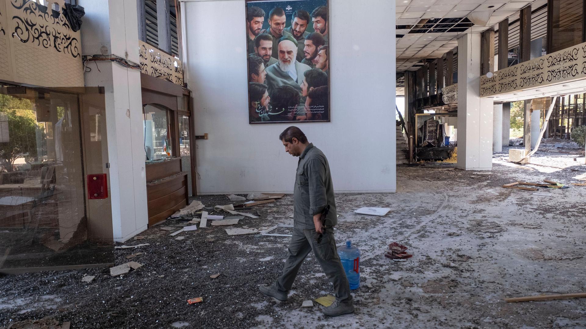 Ein Mann geht an einem Plakat vorbei, auf dem ein Porträt des verstorbenen iranischen Führers Ayatollah Khomeini zu sehen ist. Das Gebäude des iranischen Staatsfernsehens wurde durch israelische Angriffe zerstört.
Ein Mann geht an einem Plakat vorbei, auf dem ein Porträt des verstorbenen iranischen Führers Ayatollah Khomeini zu sehen ist. Das Gebäude des iranischen Staatsfernsehens wurde durch israelische Angriffe zerstört.