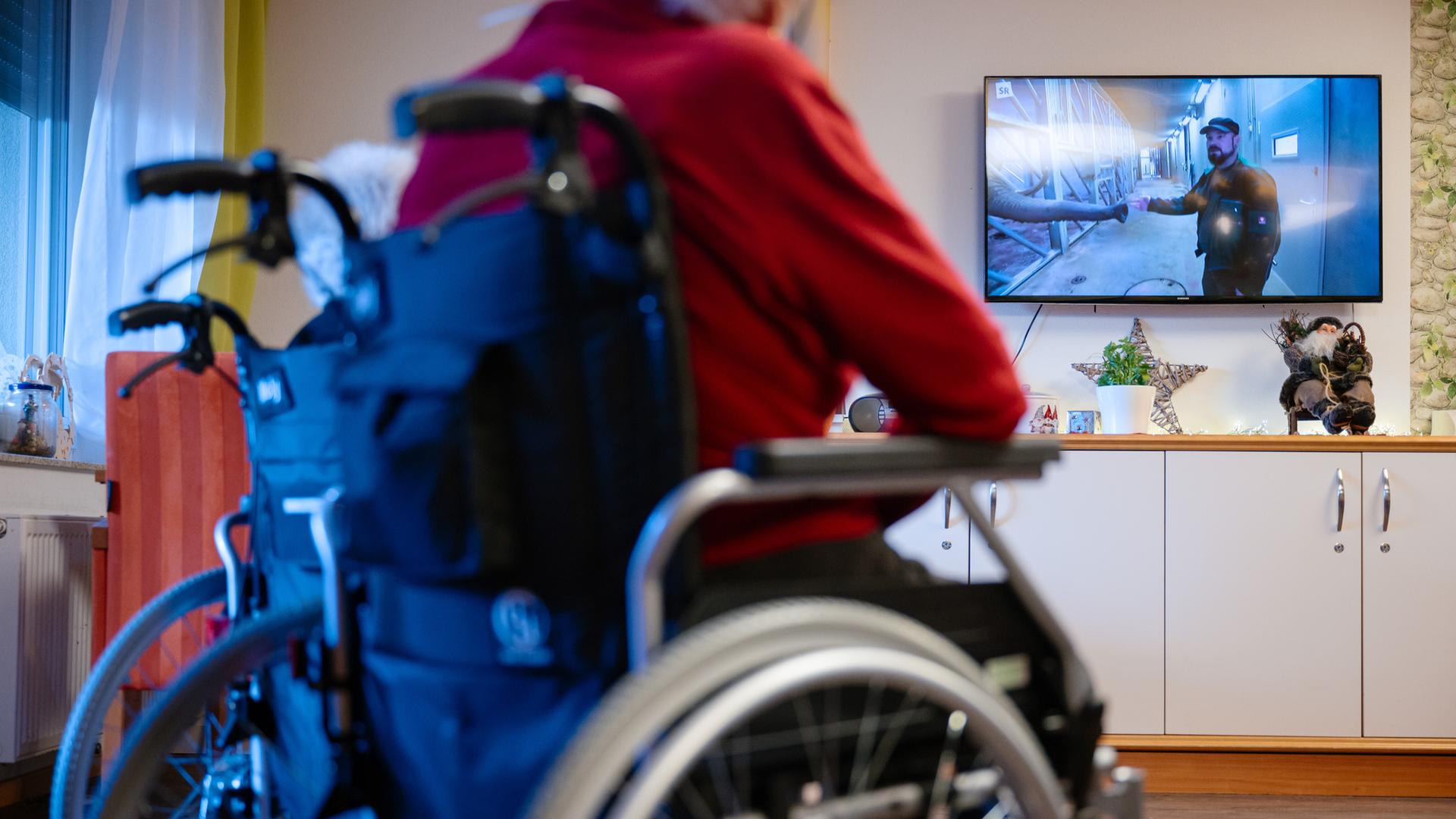 Bewohner eines Senioren- und Pflegezentrums sitzen im Aufenthaltsraum und schauen Fernsehen. 