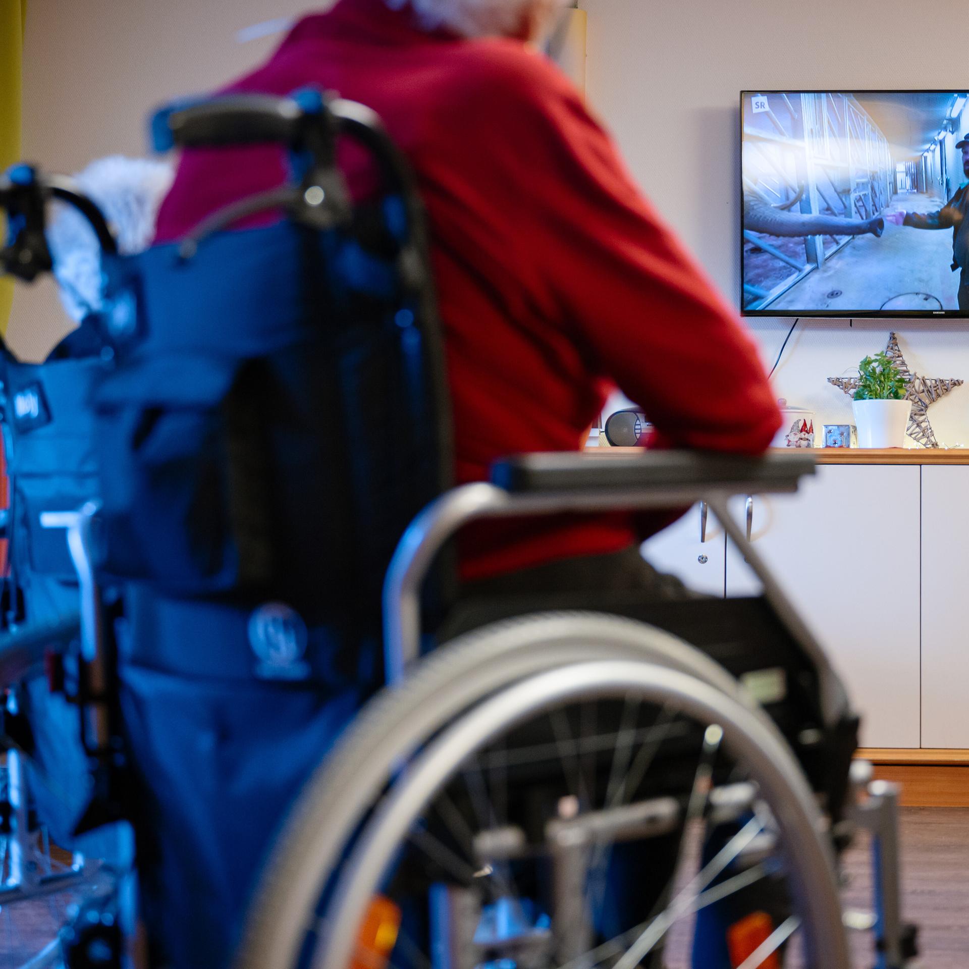 Bewohner eines Senioren- und Pflegezentrums sitzen im Aufenthaltsraum und schauen Fernsehen. 