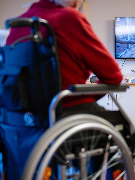 Bewohner eines Senioren- und Pflegezentrums sitzen im Aufenthaltsraum und schauen Fernsehen. 