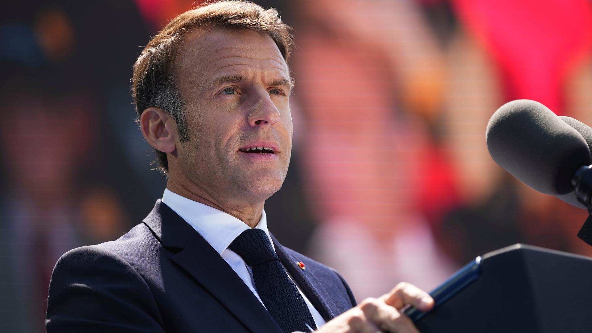 Der französische Präsident Emmanuel Macron hält eine Rede während einer Gedenkveranstaltung zum 80. Jahrestag des D-Day auf dem US-Friedhof in der Normandie. Er trägt ein dunkles Sakko, dunkle Krawatte und weißes Hemd, steht an einem Rednerpult an zwei Mikrofonen und blickt ernst in die Kamera. Der französische Präsident Emmanuel Macron hält eine Rede während einer Gedenkveranstaltung zum 80. Jahrestag des D-Day auf dem US-Friedhof in der Normandie. Er trägt ein dunkles Sakko, dunkle Krawatte und weißes Hemd, steht an einem Rednerpult an zwei Mikrofonen und blickt ernst in die Kamera.