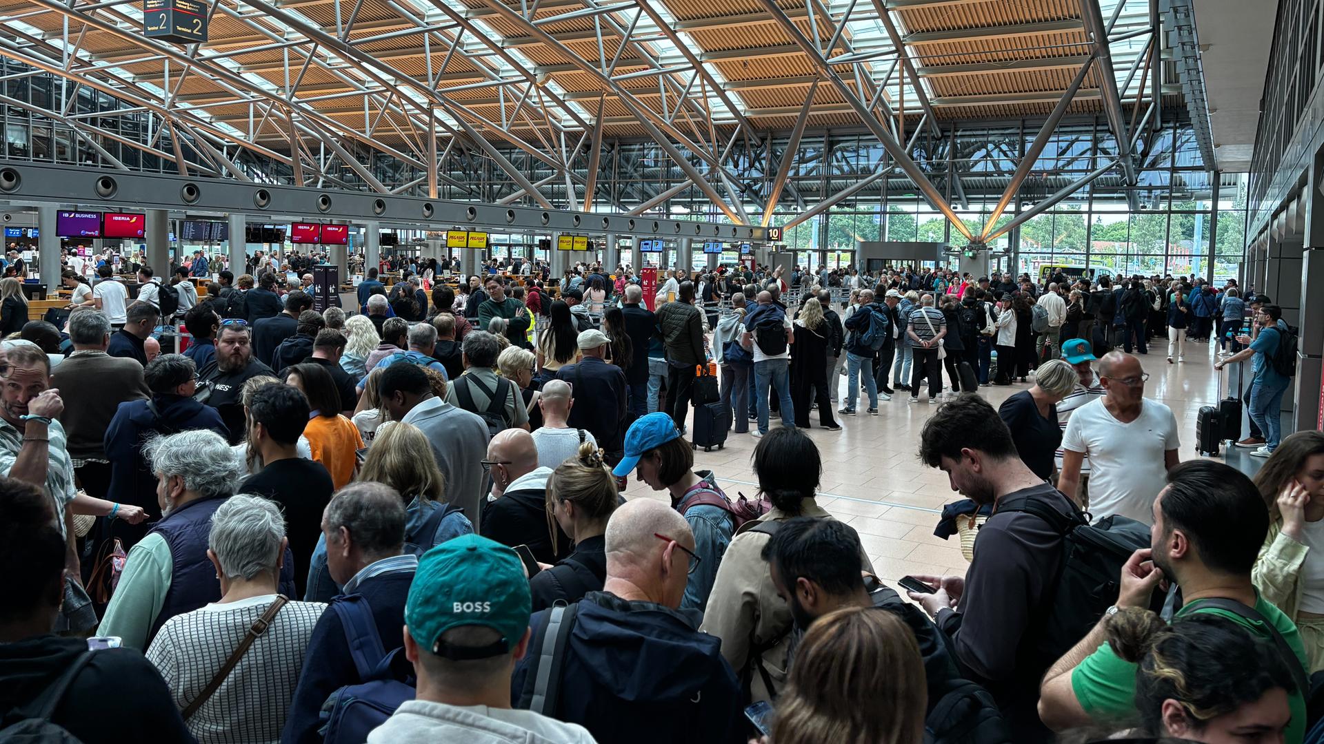 Menschen stehen in einer Halle am Flughafen in Hamburg. Menschen stehen in einer Halle am Flughafen in Hamburg.