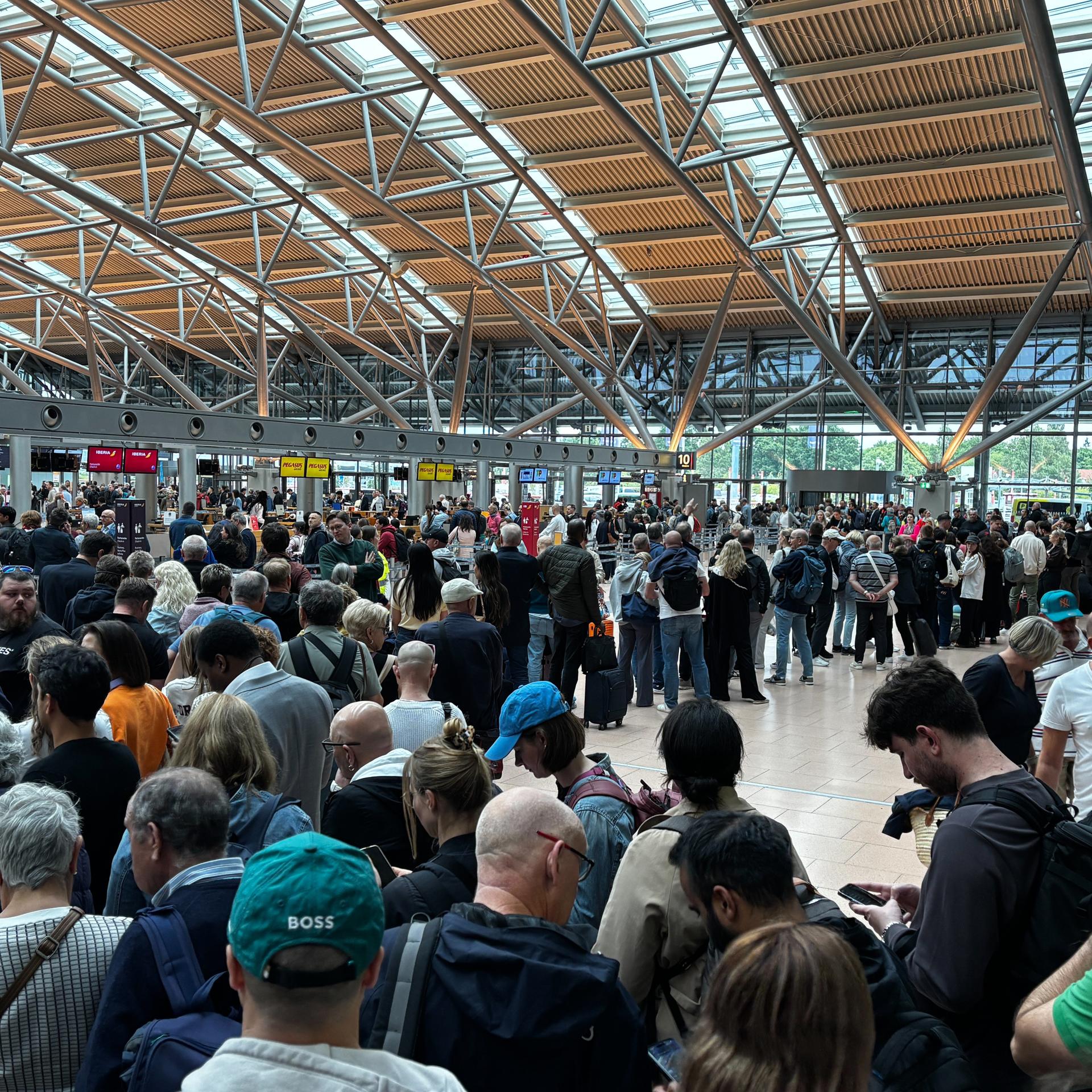 Menschen stehen in einer Halle am Flughafen in Hamburg.  