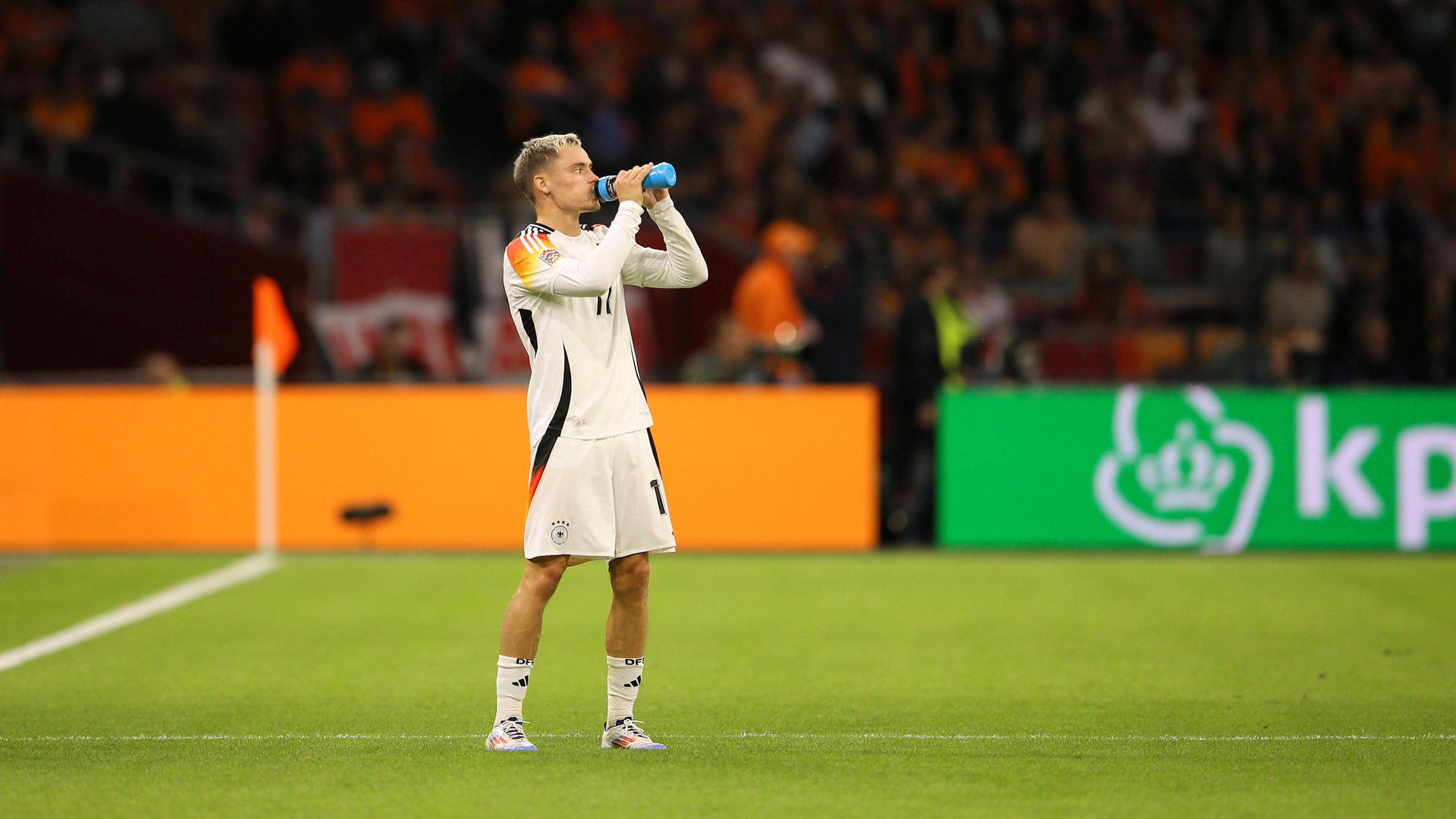 Florian Wirtz trägt das Trikot der deutschen Nationalmannnschaft und trinkt aus einer Flasche.