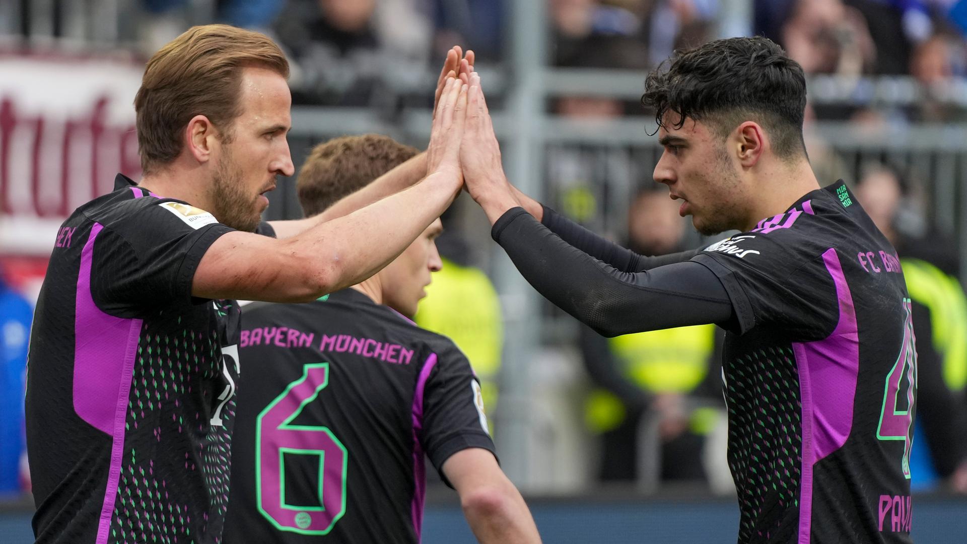 Die Bayern-Teamkollegen Harry Kane und Jamal Musiala klatschen nach einem gemeinsamen Tor in Darmstadt ab.