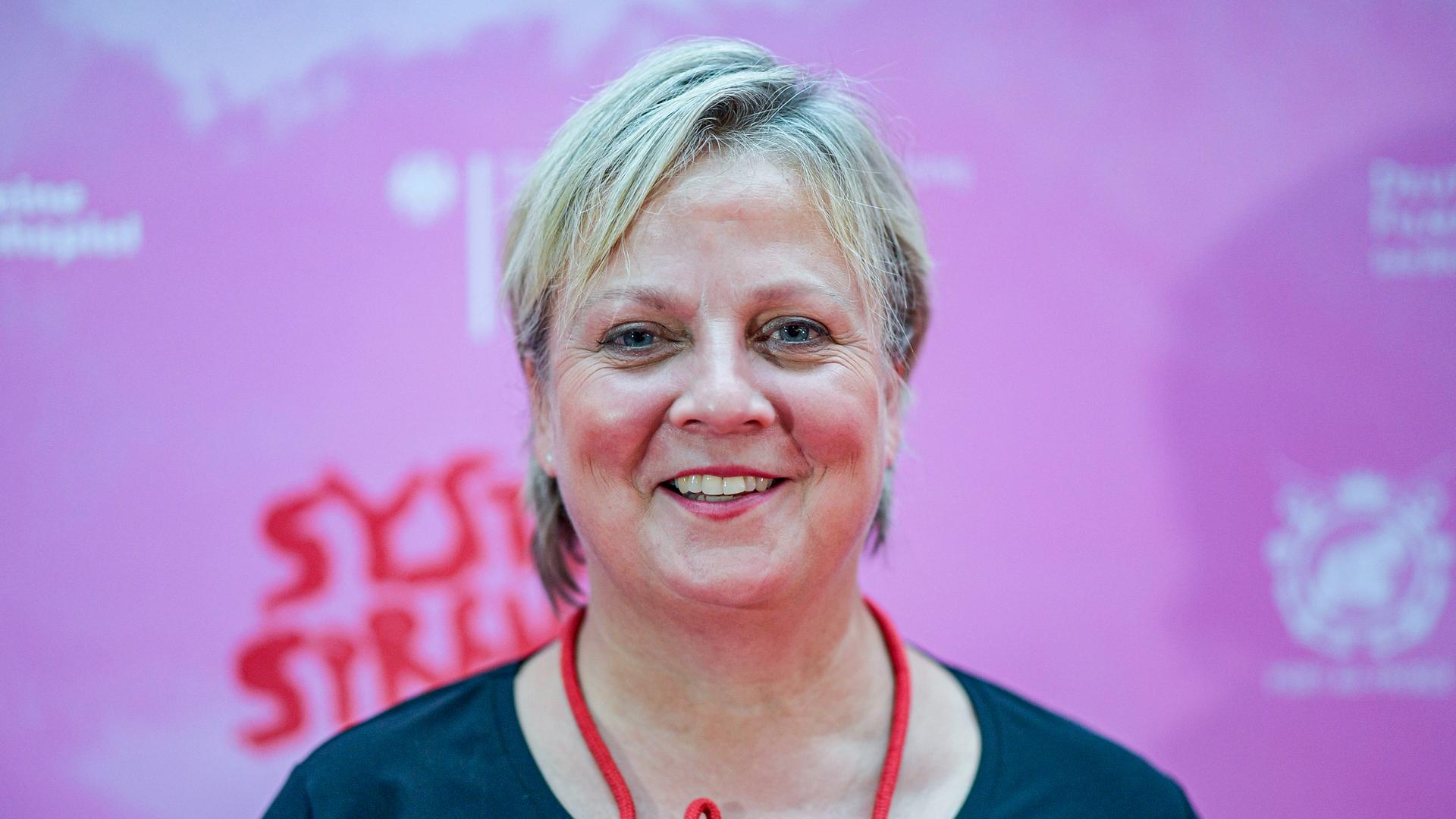 Eine blonde Frau lächelt in die Kamera. Ihre Wangen sind mit Rouge geschminkt, um den Hals trägt sie eine "Ahoi"-Kette. Eine blonde Frau lächelt in die Kamera. Ihre Wangen sind mit Rouge geschminkt, um den Hals trägt sie eine "Ahoi"-Kette.