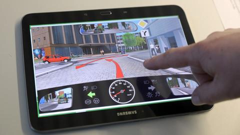 Ein Tablet zeigt eine Verkehrssituation bei einer theoretischen Führerschein-Prüfung.
