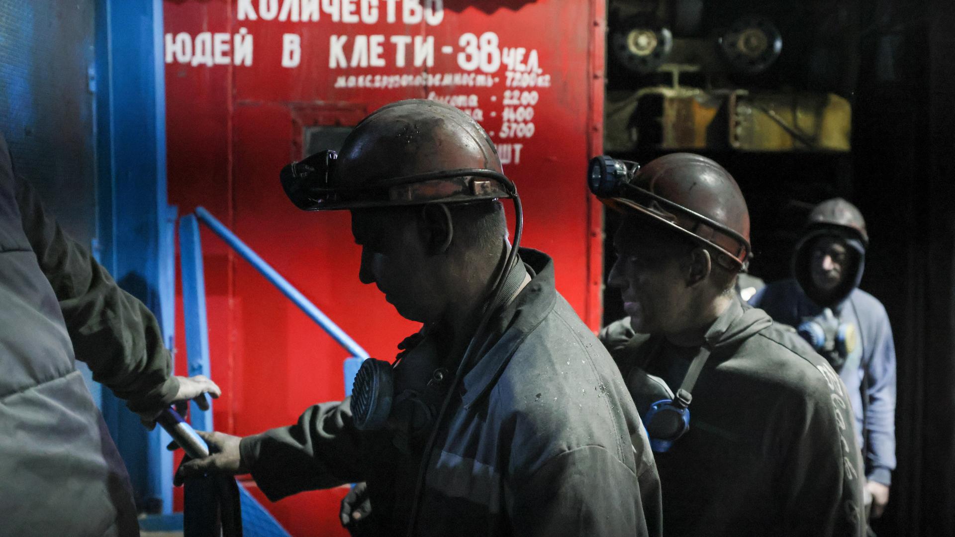 Russische Minenarbeiter gehen in Arbeitskleidung und bedeckt mit schwarzem Kohlestaub vorbei am Tor der Kohlemine Dolzhanskaya-Kapitalnaya im von Russland kontrollierten Luhansk-Gebiet in der Osktukraine. Russische Minenarbeiter gehen in Arbeitskleidung und bedeckt mit schwarzem Kohlestaub vorbei am Tor der Kohlemine Dolzhanskaya-Kapitalnaya im von Russland kontrollierten Luhansk-Gebiet in der Osktukraine.