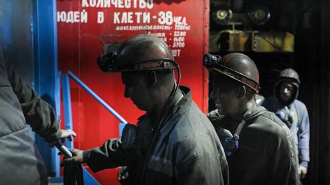 Russische Minenarbeiter gehen in Arbeitskleidung und bedeckt mit schwarzem Kohlestaub vorbei am Tor der Kohlemine Dolzhanskaya-Kapitalnaya im von Russland kontrollierten Luhansk-Gebiet in der Osktukraine.