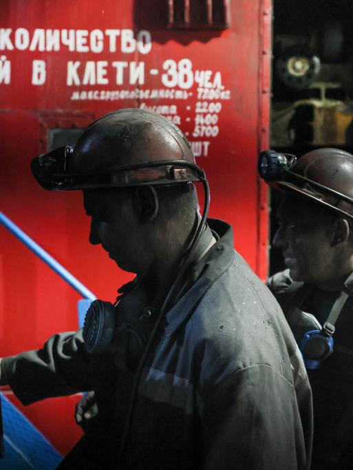 Russische Minenarbeiter gehen in Arbeitskleidung und bedeckt mit schwarzem Kohlestaub vorbei am Tor der Kohlemine Dolzhanskaya-Kapitalnaya im von Russland kontrollierten Luhansk-Gebiet in der Osktukraine.