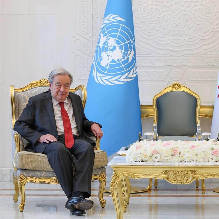 UNO-Generalsekretär Guterres und der syrische Übergangspräsident al-Scharaa sitzen auf zwei großen Stühlen nebeneinander, mit einigem Abstand zwischen ihnen. Hinter ihnen stehen die Flaggen der Vereinten Nationen und Syriens.
