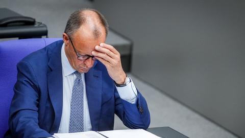Bundeskanzler Friedrich Merz sitzt nachdenklich an seinem Platz im Plenarsaal des Bundestages