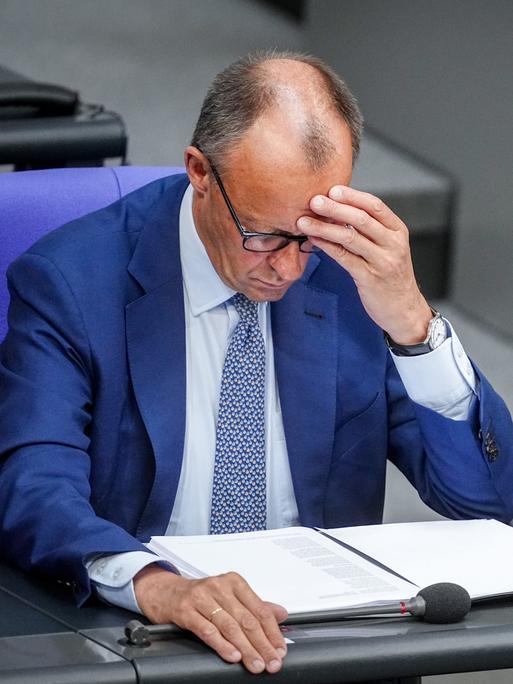 Bundeskanzler Friedrich Merz sitzt nachdenklich an seinem Platz im Plenarsaal des Bundestages