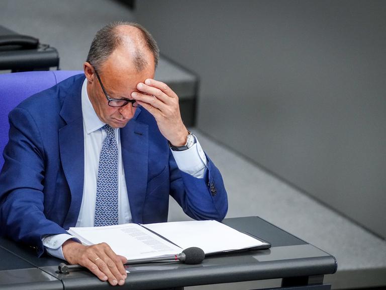 Bundeskanzler Friedrich Merz sitzt nachdenklich an seinem Platz im Plenarsaal des Bundestages
