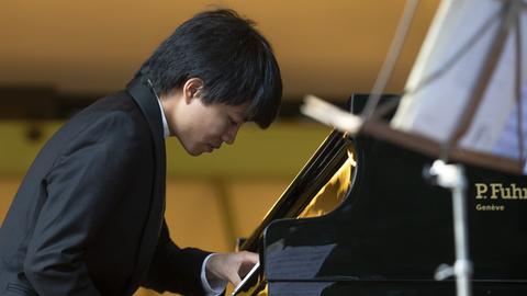 Der Pianist Kit Armstrong spielt an einem Flügel.