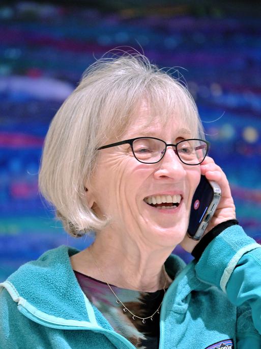 Eine Frau Mitte siebzig, die US-Wirtschaftswissenschaftlerin Claudia Goldin, telefoniert und lächelt dabei. Sie hat graue, halblange Haare, und träge eine Brille mit schmalem, dunklen Rand.