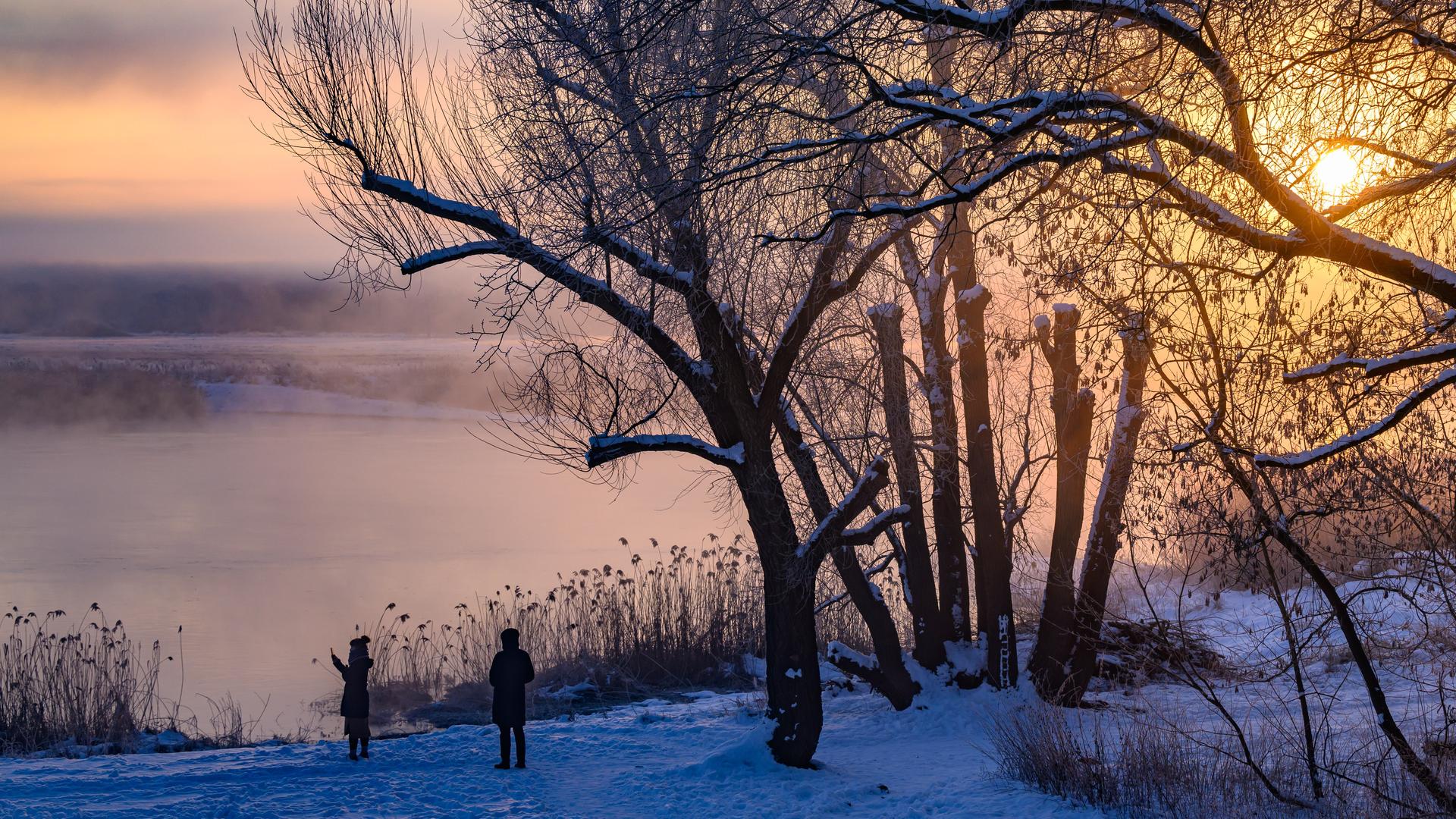 Sonnen-Aufgang in Brandenburg. Zwei Personen stehen in einer Winterlandschaft. Sonnen-Aufgang in Brandenburg. Zwei Personen stehen in einer Winterlandschaft.