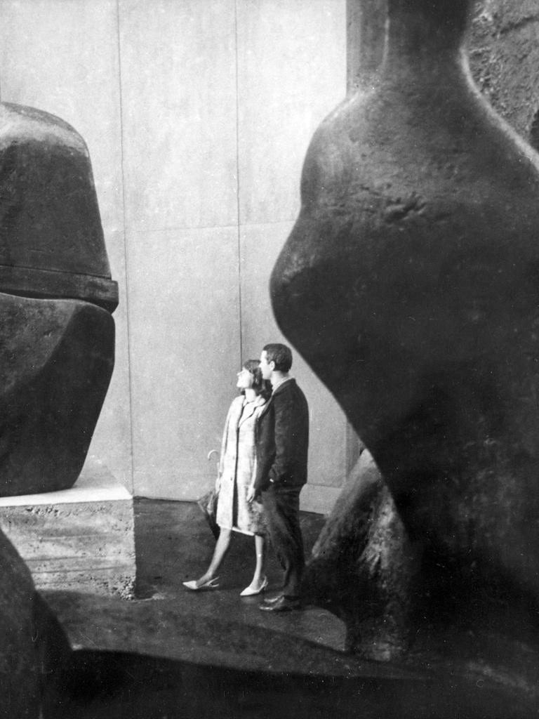 Historisches Schwarzweißfoto eines jungen Paares, das Steinskulpturen in einer Halle betrachtet.