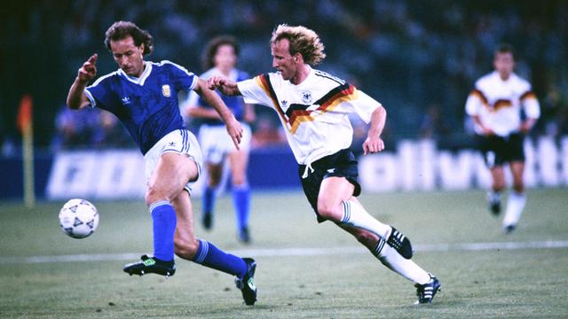 Andreas Brehme bei der Fußball-WM 1990. Er kämpft mit einem Spieler von dem Land Argentinien um den Ball. 
