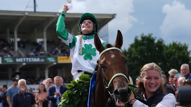 Nina Baltromei sitzt auf dem Pferd "Hochkönig" und jubelt nach ihrem Sieg beim Galopp-Derby.