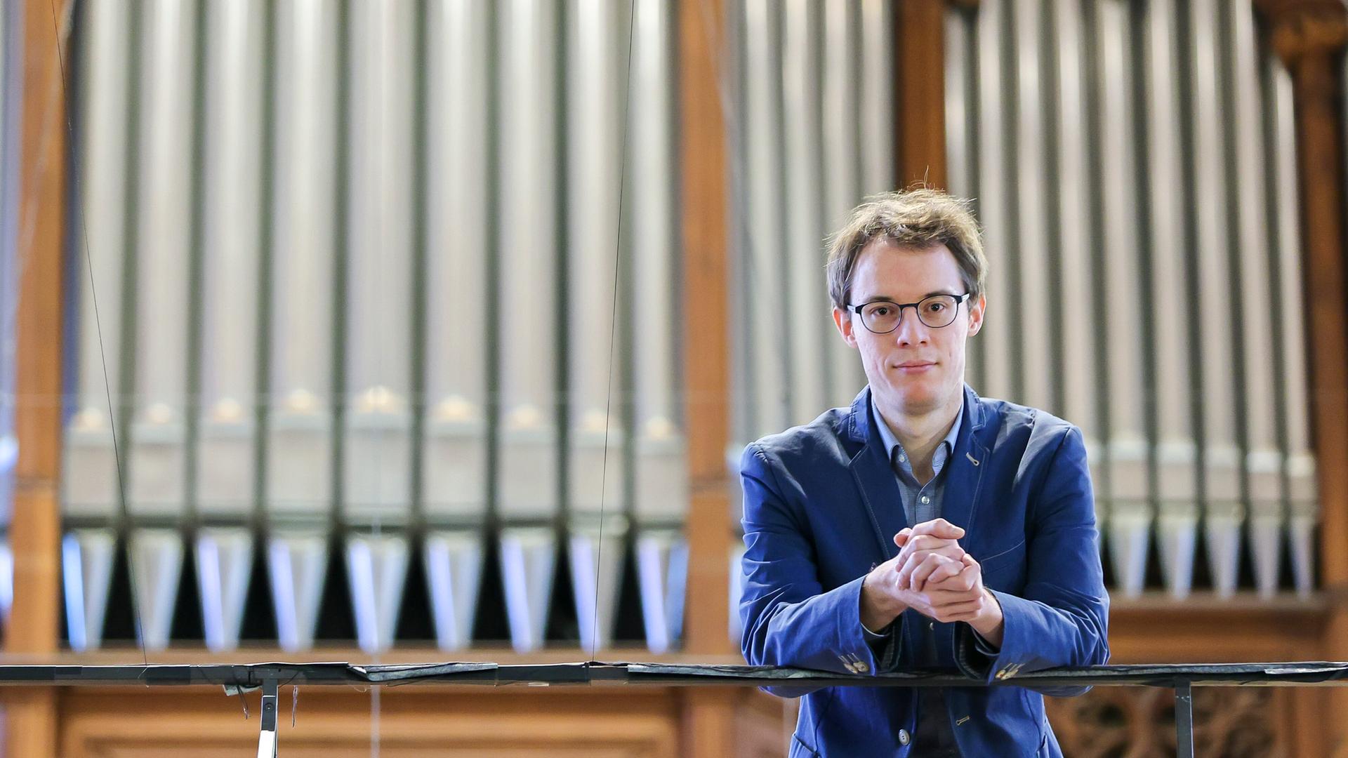 Johannes Lang, Organist der Leipziger Thomaskirche, steht auf der Orgelempore vor dem Instrument. 