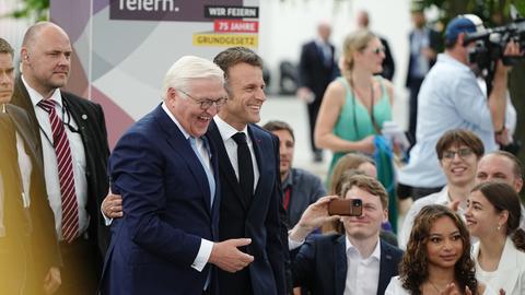 Frankreichs Präsident Emmanuel Macron und Bundespräsident Frank-Walter Steinmeier besuchen das Demokratiefest und lachen mit den Besuchern.