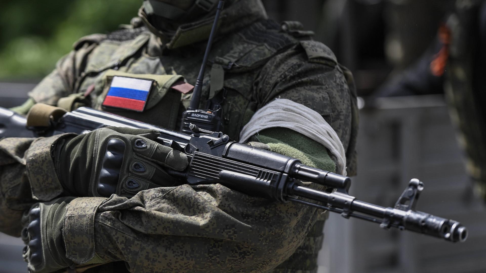 Ein russischer Soldat hat ein Maschinengewehr über den Arm gelegt.